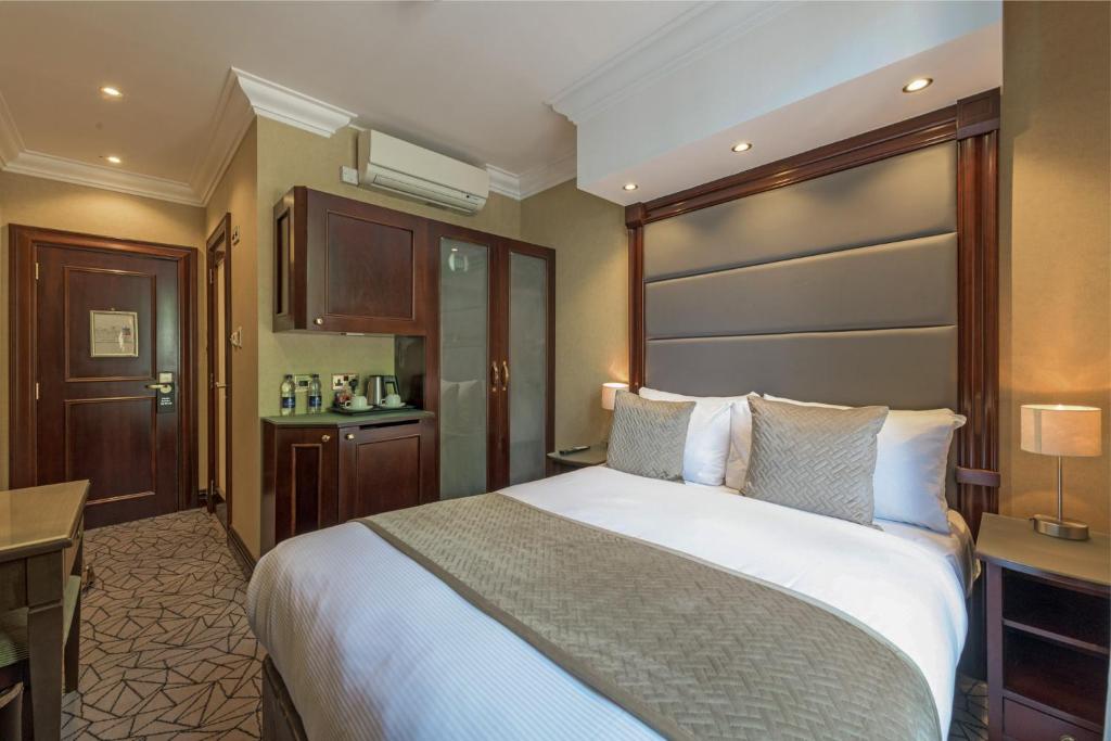 伦敦Hyde Park International的酒店客房设有一张大床和一张书桌。