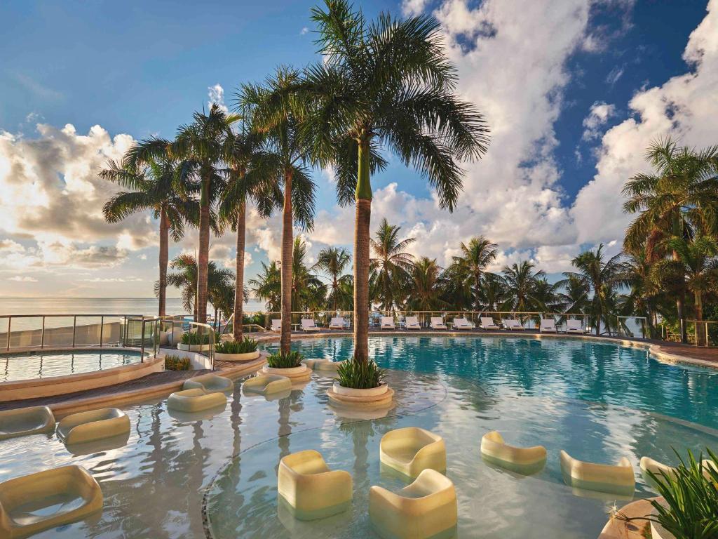 麦克坦宿务麦丹岛慕温匹克酒店的一个带椅子和棕榈树的大型游泳池