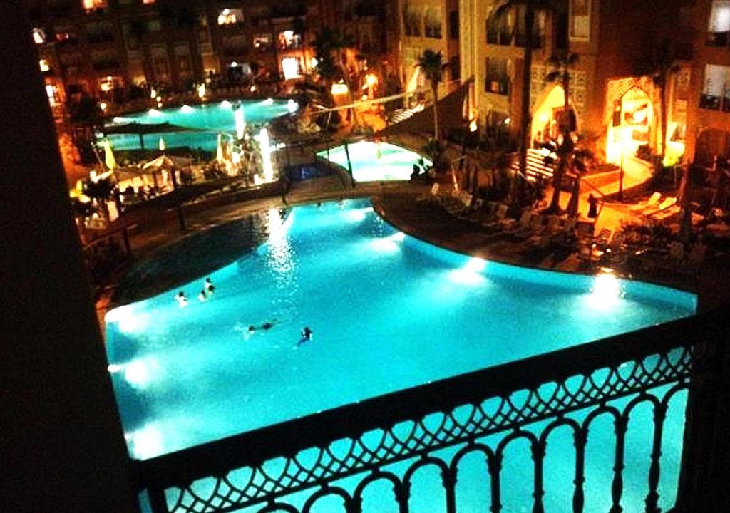 El Ahmarappart très luxueux 6 personnes的一个大型游泳池,人们晚上在游泳池游泳
