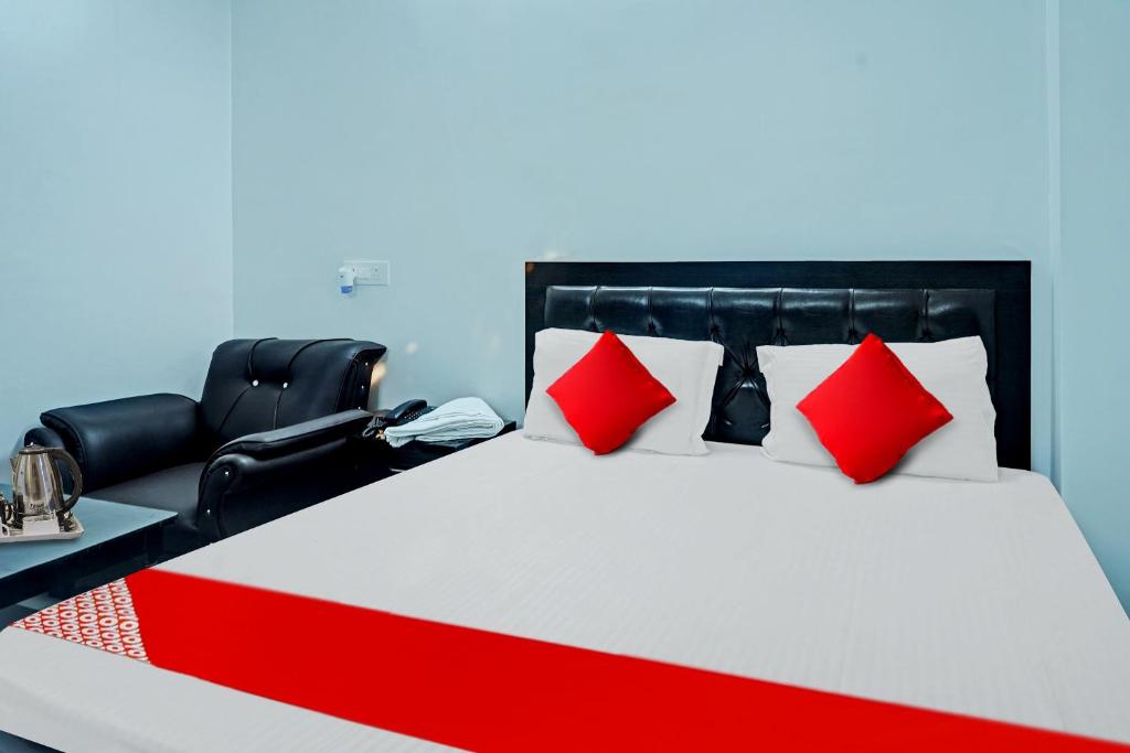 巴特那Flagship Hotel The Pinkcity的一间卧室配有一张带红色枕头的床和一把椅子