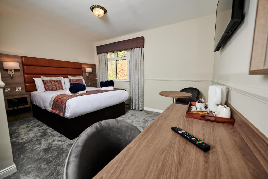 科尔雷恩Bushtown Hotel & Spa的酒店客房设有一张床和一张带遥控器的书桌