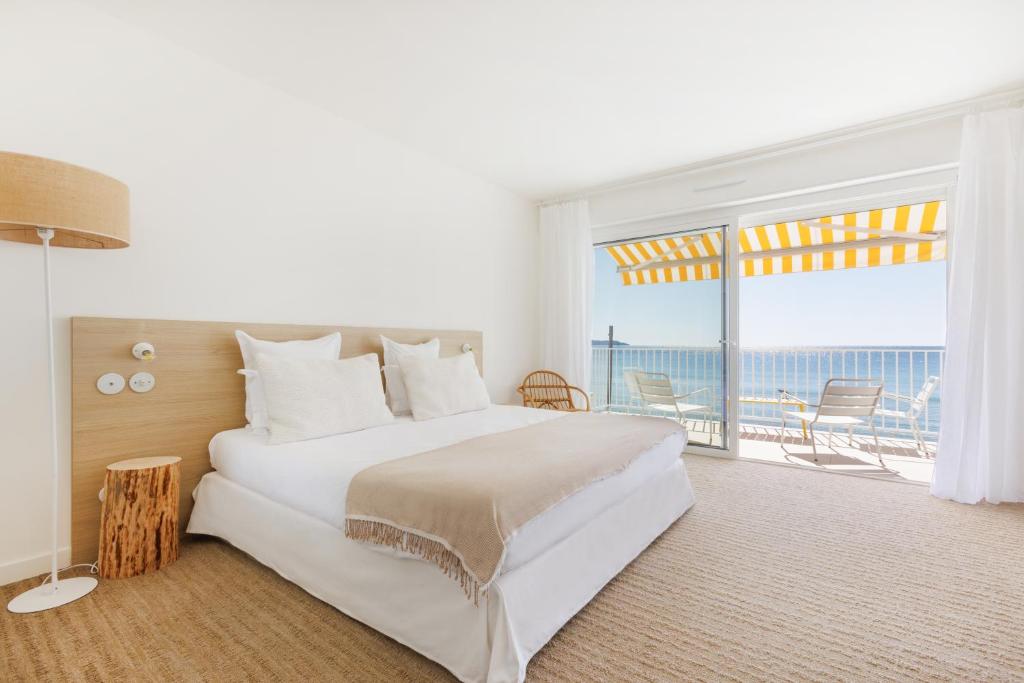 滨海卡瓦莱尔Belle Vue Hôtel的一间卧室设有一张大床和一个大窗户