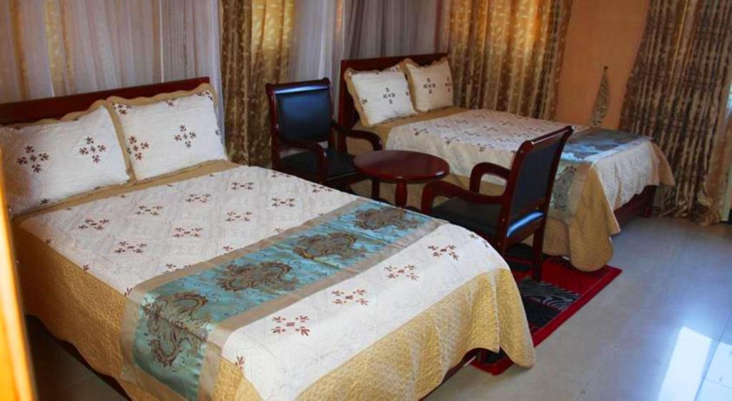 坎帕拉Pearl Highway Hotel Kibuye Kampala的酒店客房,配有两张床和两把椅子