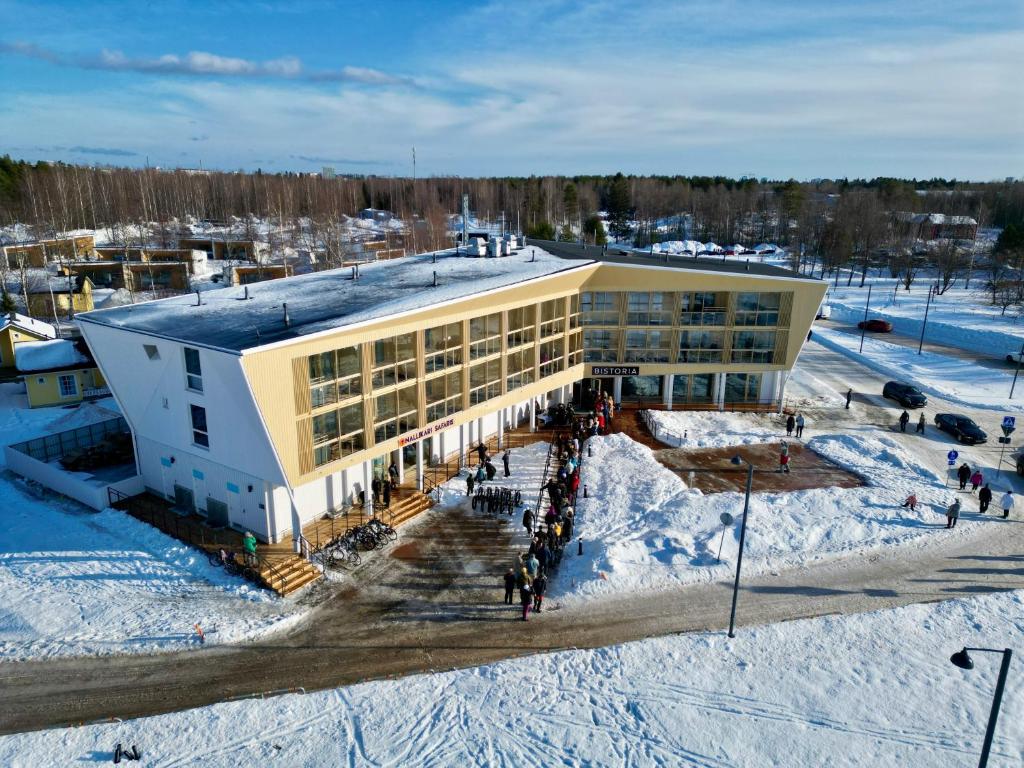 奥卢Nallikari Holiday Village - Aalto Seaside Apartments的雪中的一个建筑,人们站在它外面