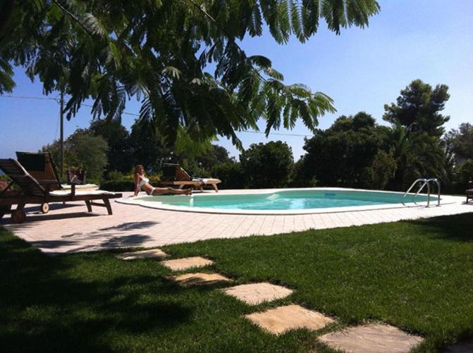 努马纳Appartamento sulla Riviera del Conero的坐在游泳池旁椅子上的女人