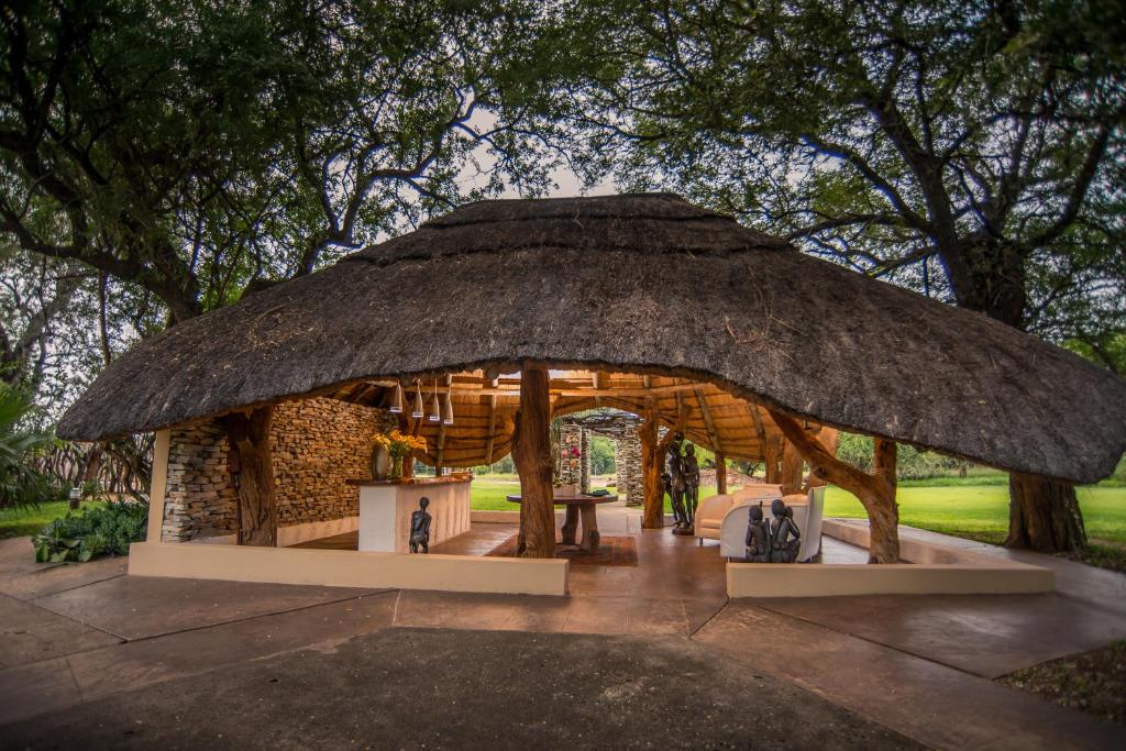 Karongwe Game ReserveKarongwe River Lodge的茅草屋顶小屋和桌子