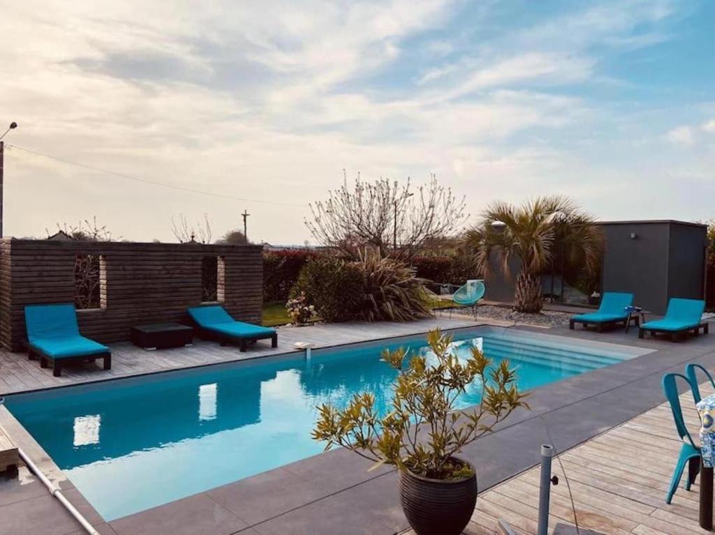 La Guerche-de-BretagneJolie maison avec piscine et Spa的一座带蓝色椅子的游泳池,位于大楼旁