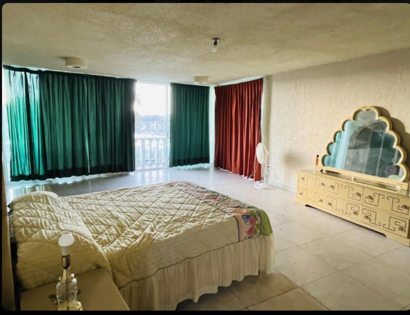 阿卡普尔科Casa con vista espectacular al mar con alberca的一间卧室配有一张带绿色窗帘的大床