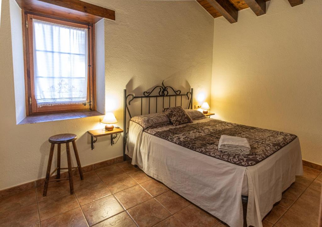 坎姆帕拉斯Can Tubau - Casa rural - Apartaments的一间卧室设有床、窗户和凳子
