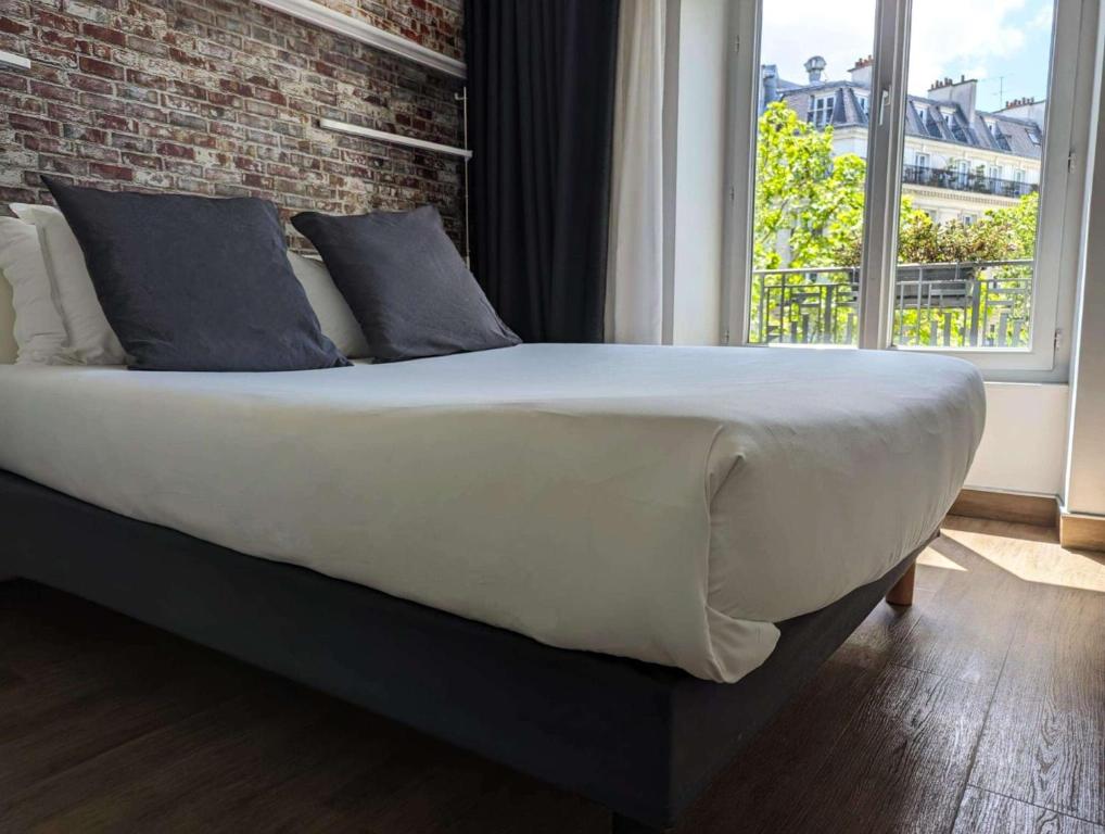 巴黎贝斯特韦斯特巴纳斯峰酒店的卧室内的一张大床,卧室设有砖墙