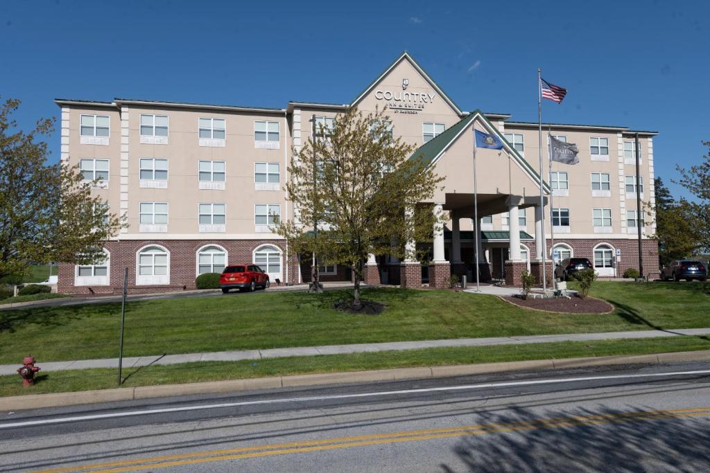 哈里斯堡Country Inn & Suites by Radisson, Harrisburg - Hershey West, PA的前面有美国国旗的建筑