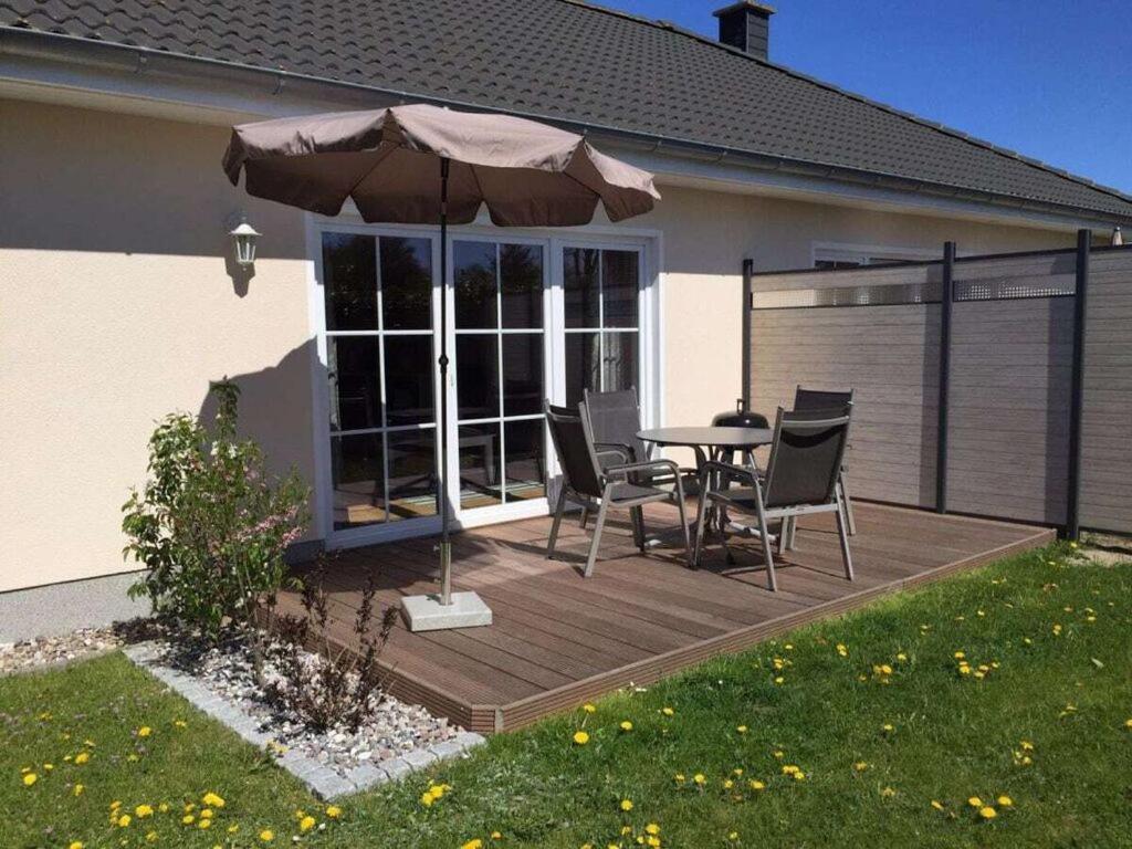 普鲁滕Boddensurfer 2b Comfortable holiday residence的庭院配有桌椅和遮阳伞。
