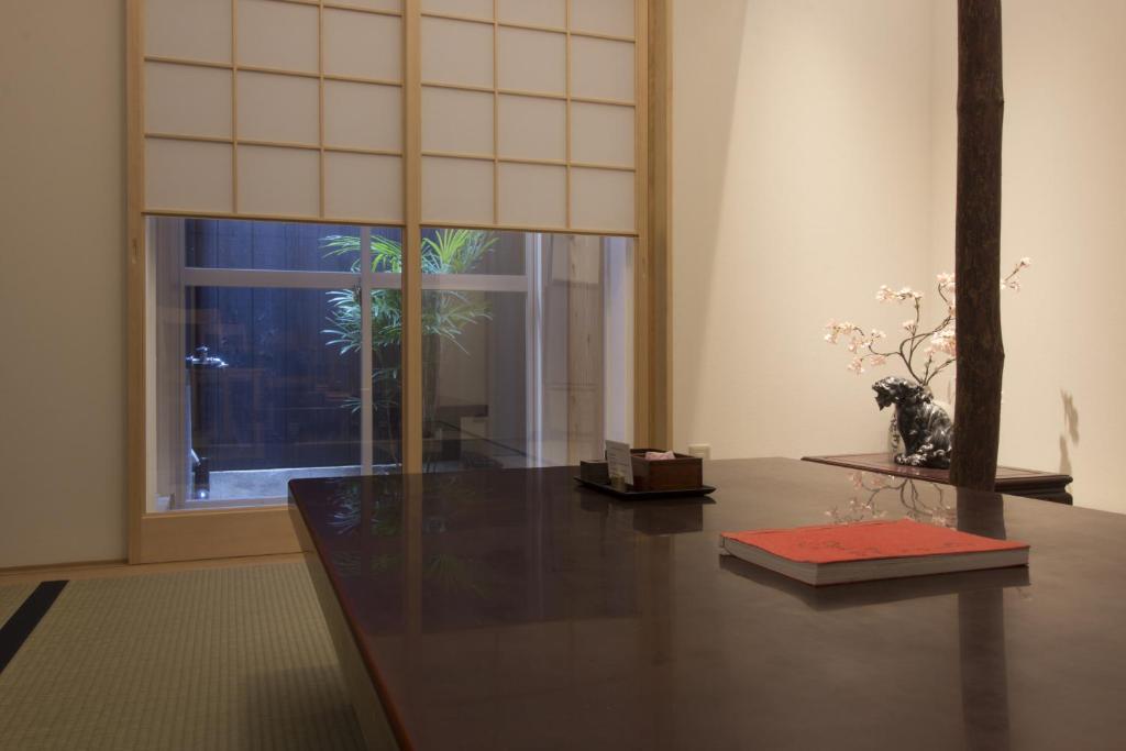 京都Gion House的一间设有桌子的房间和一个种植了植物的窗户