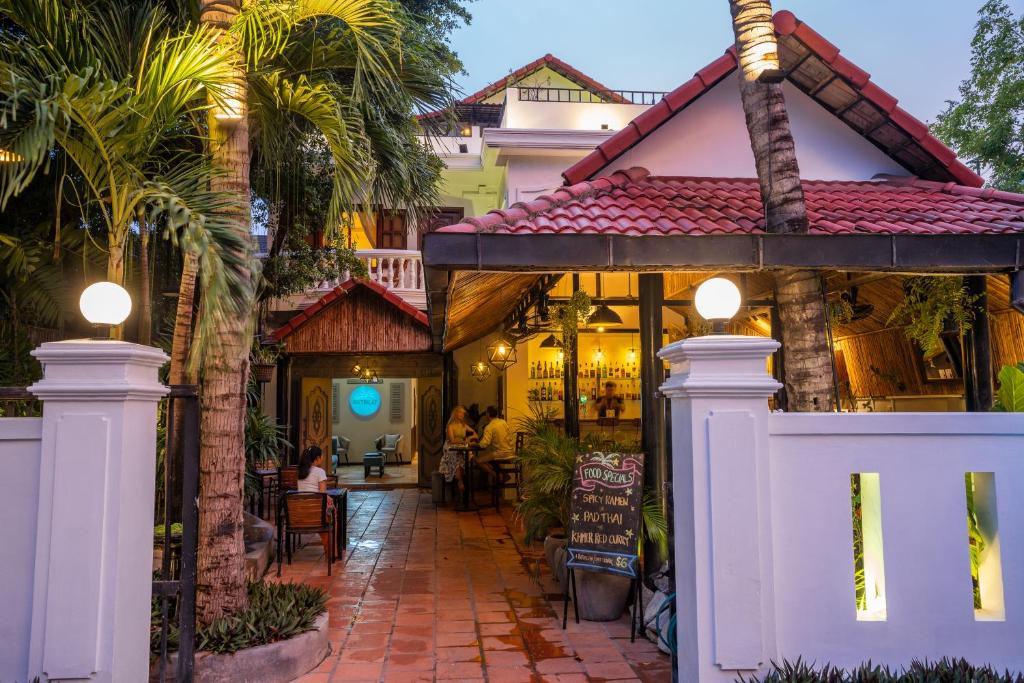 暹粒River Retreat Boutique Hotel的一座白色大门和棕榈树的房子