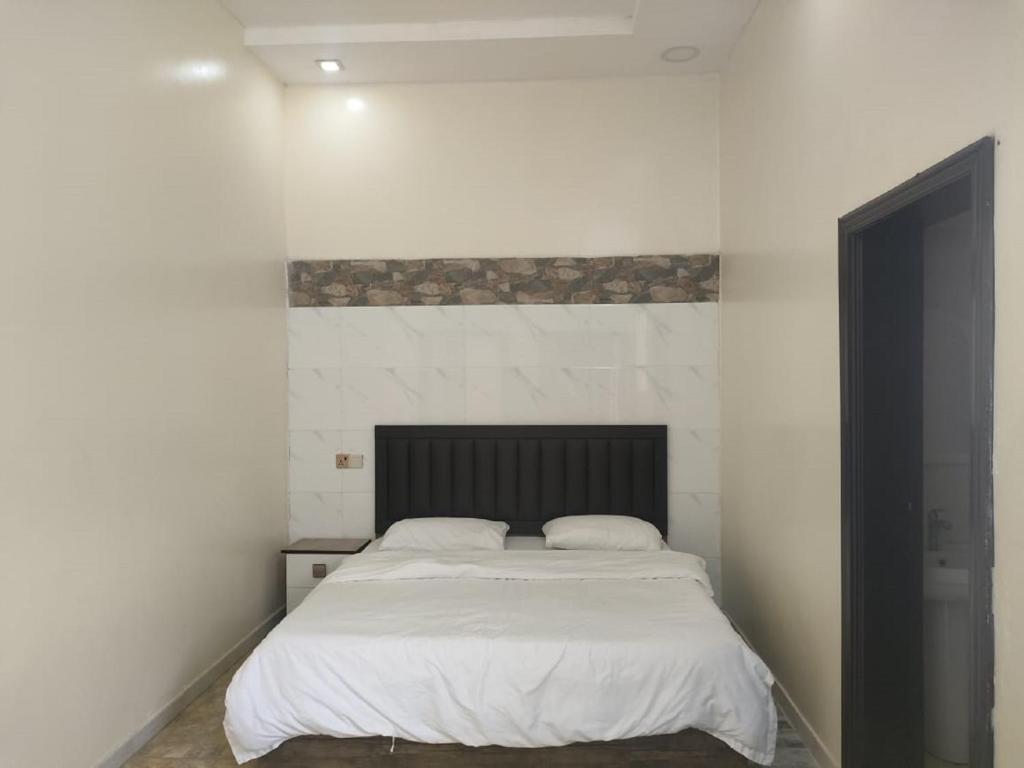 Qāʼidاستراحات توليب أبها的一间卧室配有一张白色的床和黑色床头板