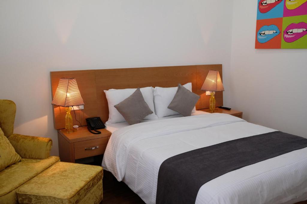 第比利斯第比利斯华凌酒店的一间卧室配有一张床、一把椅子和两盏灯。