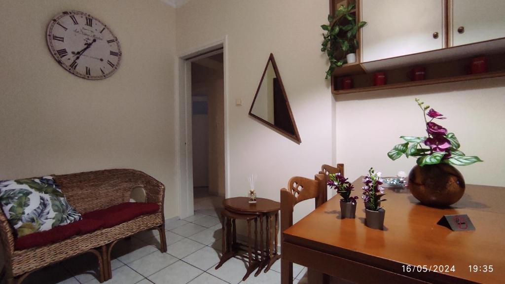 希俄斯Διαμέρισμα στο Κέντρο της Χίου的客厅配有桌子和墙上的时钟
