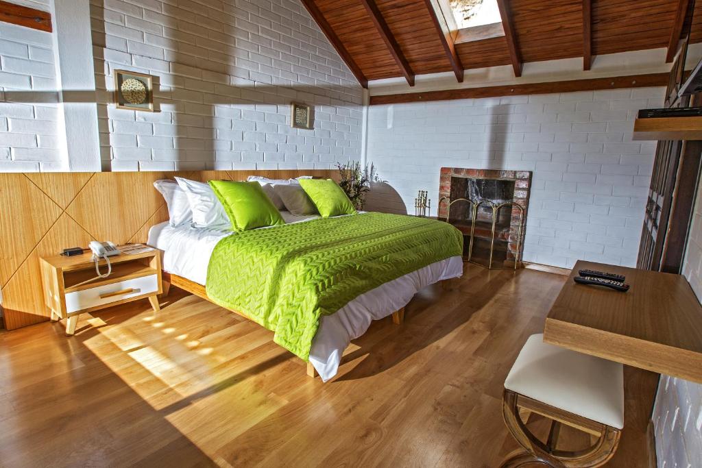 伊瓦拉Hosteria Totoral的一间卧室配有一张带绿色床单的床和一张书桌