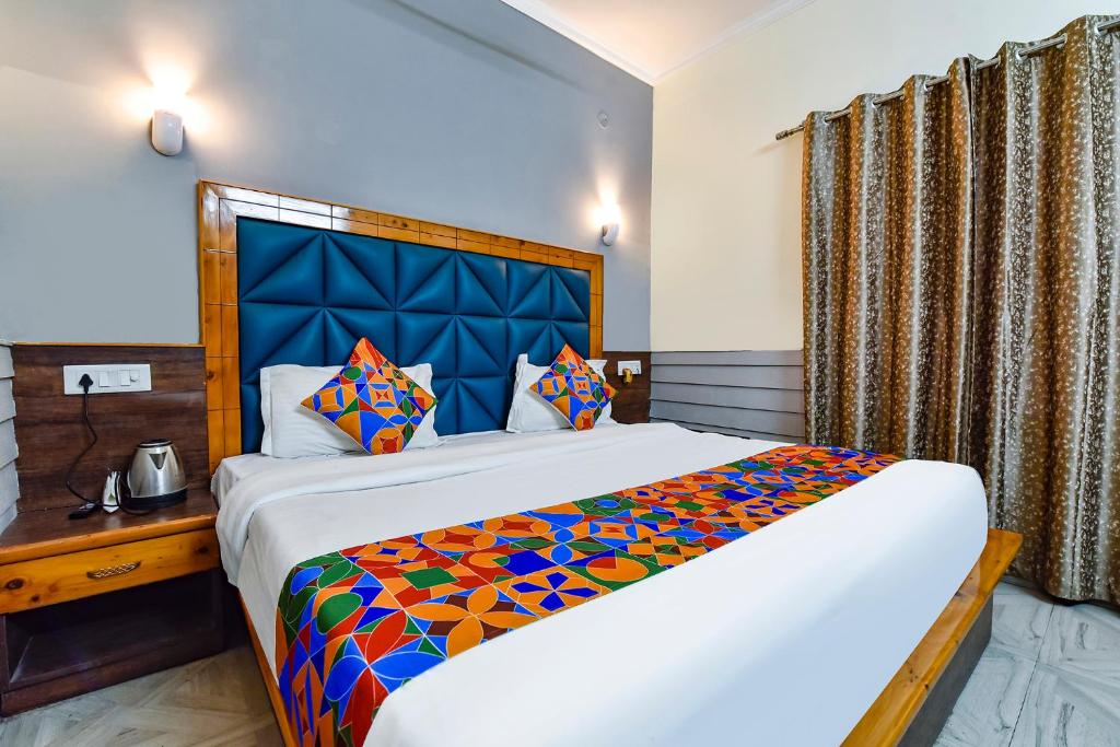 MājraFabHotel KK Residency的一间卧室配有一张大床和蓝色床头板