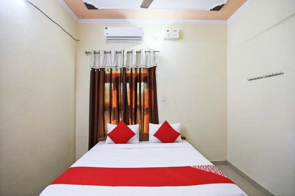 MahendragarhOYO 62761 Hotel Daksh的一间卧室配有红色枕头的床