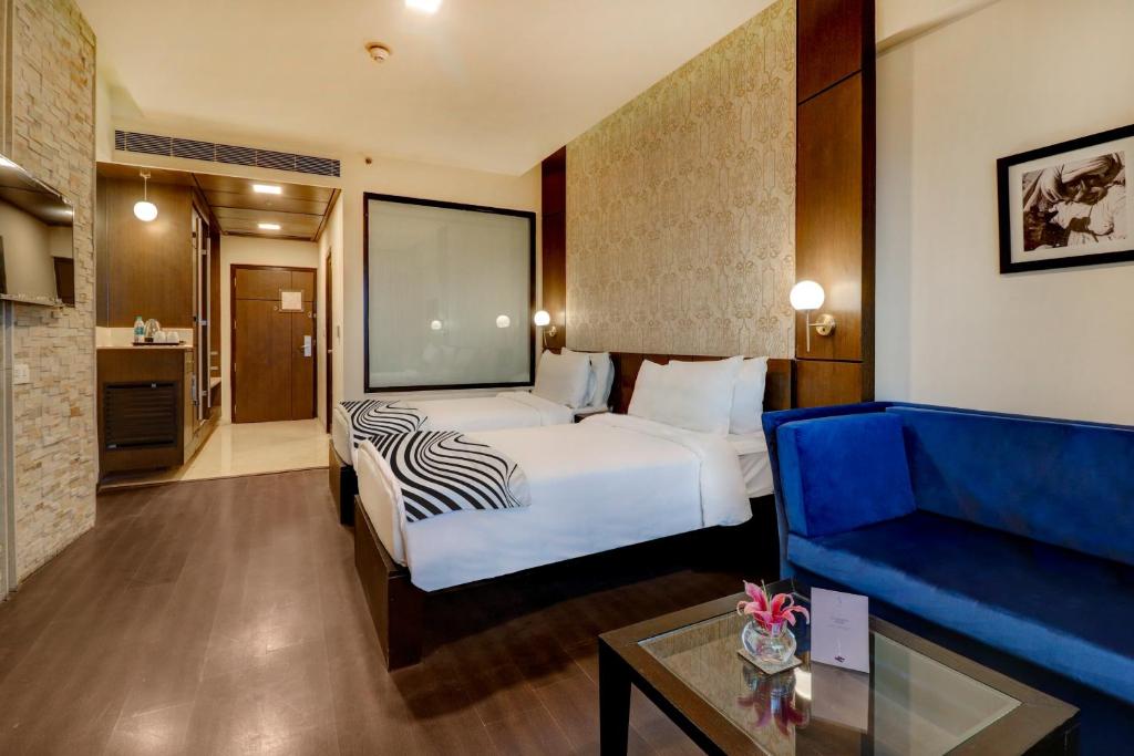 新德里Hotel Seven Villa Near Delhi Airport的酒店客房,配有床和蓝色的沙发