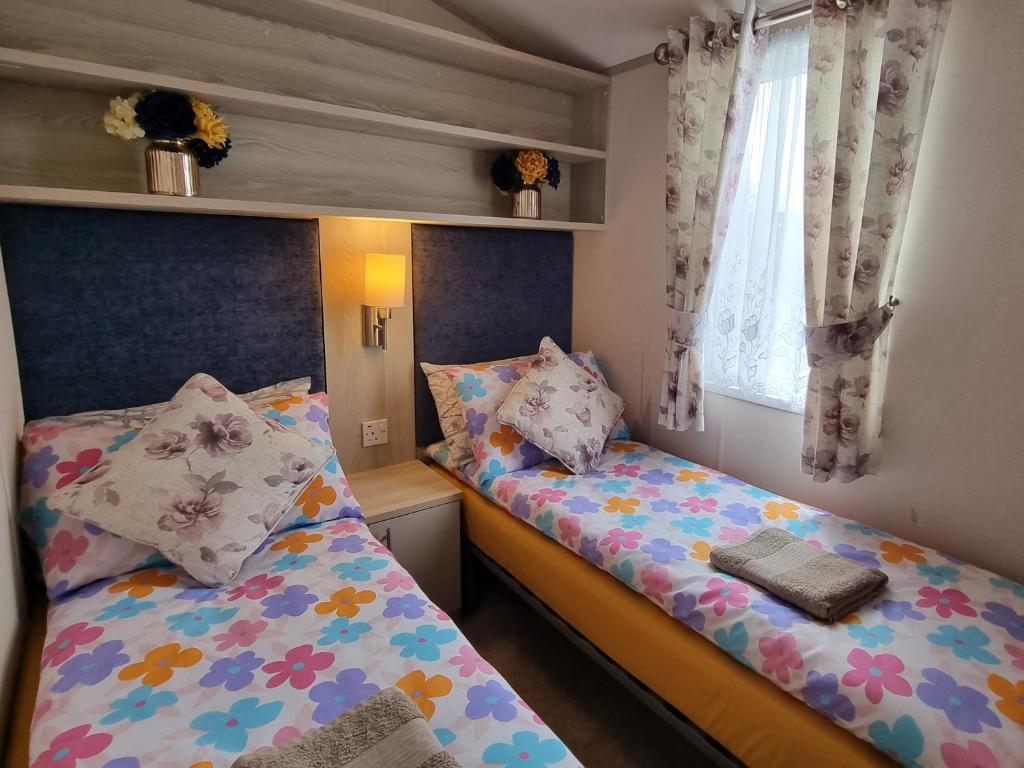 古德瑞同Static Caravan to Hire , Hoburne Devon Bay ( Paignton)的一间卧室设有两张床和窗户。