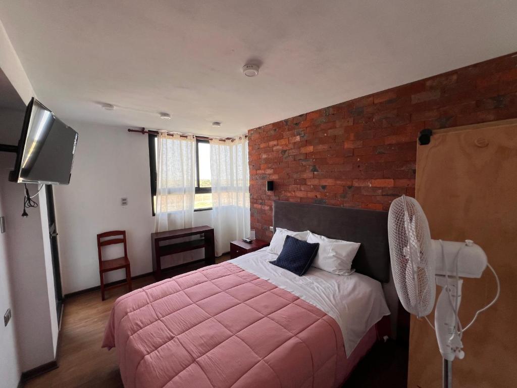 帕卡斯马约Hotel Central Pacasmayo的卧室配有粉红色的床和砖墙