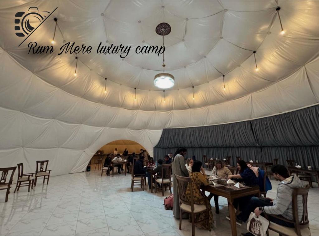 瓦迪拉姆Rum Mere luxury camp的白色帐篷,里面的人坐在桌子上