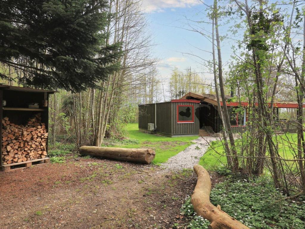 莱斯Holiday home Læsø XXV的树林里的一个小屋,有一堆木头