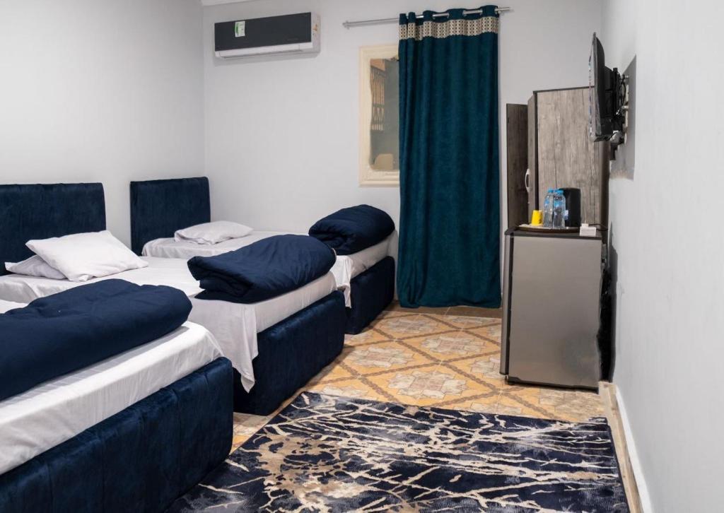 开罗Beko pyramids hotel的带3张床和蓝色枕头的客房