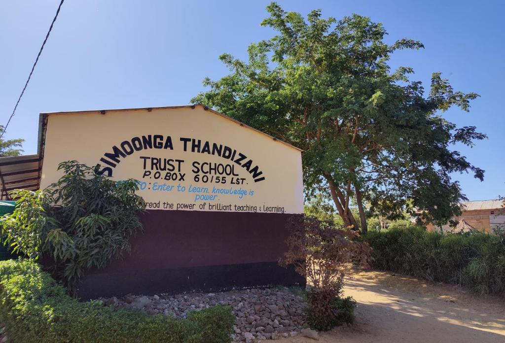 利文斯顿Simoonga Thandizani School的建筑前信托学校的标志