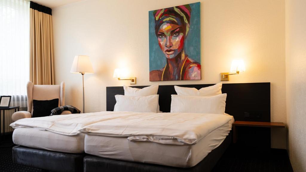 克洛彭堡克洛城堡公园酒店的卧室配有一张大床,墙上挂有绘画作品