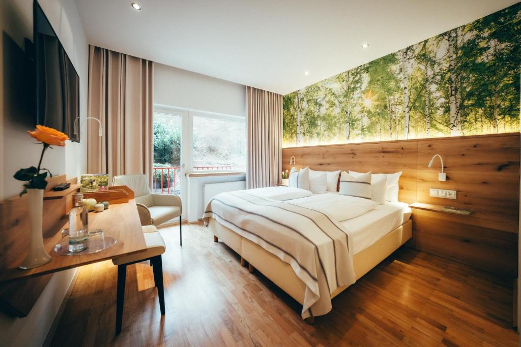 斯维斯塔尔Landidyll Hotel Weidenbrück & SPA的酒店客房设有一张大床和一张书桌。