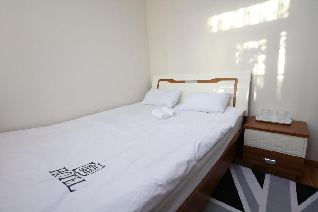 乌兰巴托Alpha Guest House的一间小卧室,配有白色的床和木制床头柜
