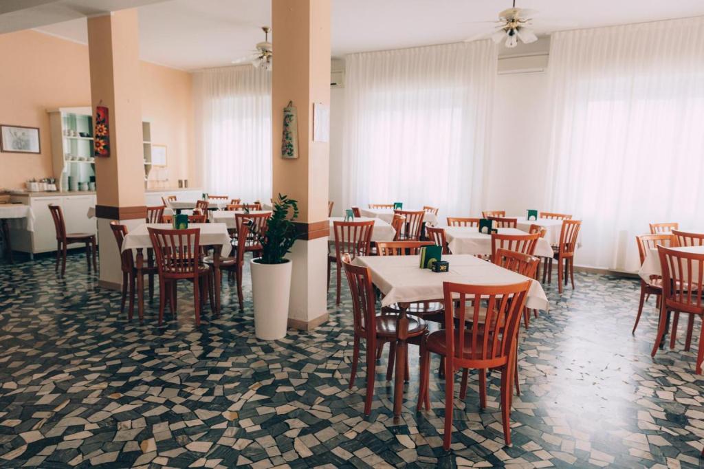 里米尼Hotel Enna Rimini的餐厅内带桌椅的用餐室