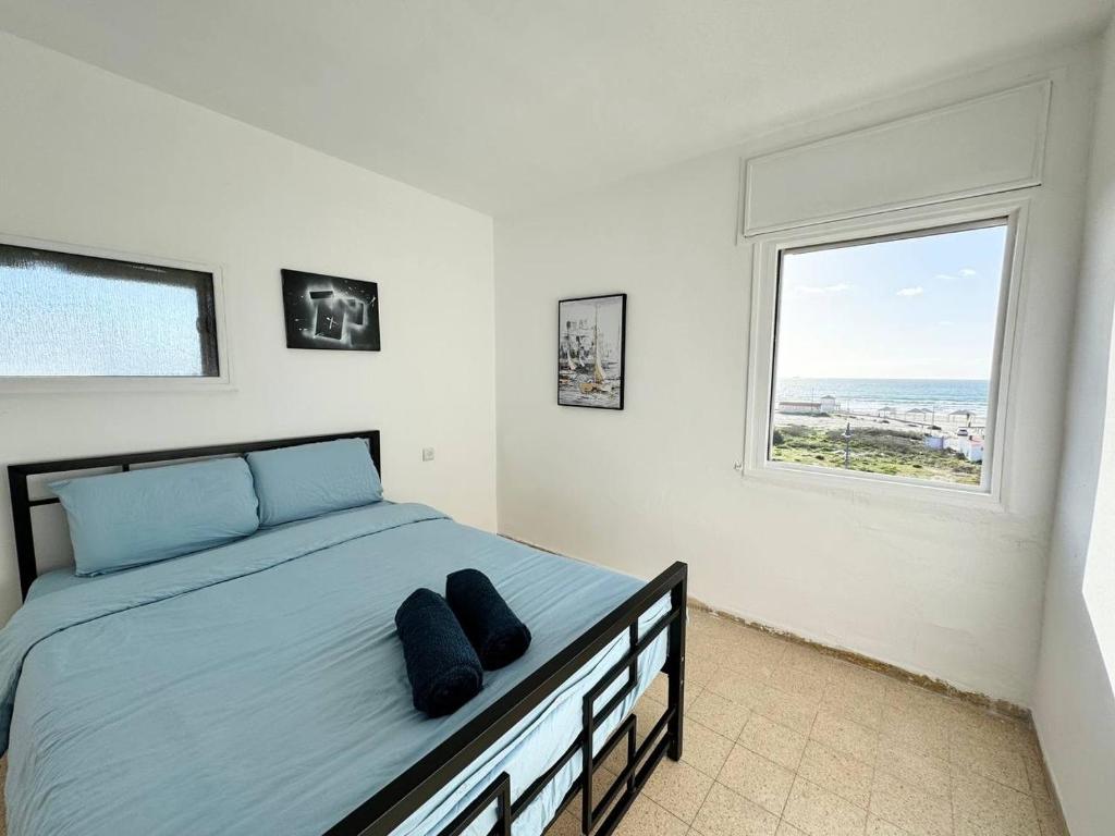 Qiryat YamAmazing sea view的一间卧室配有一张带蓝色床单的床和一扇窗户。