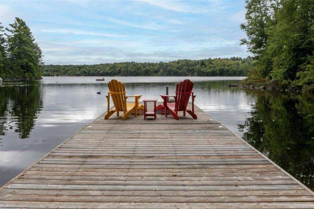 Oxtongue Lake3BR Rebecca Lakehouse with Fireplace Wifi and Dock的湖上码头上的三把椅子和一张桌子