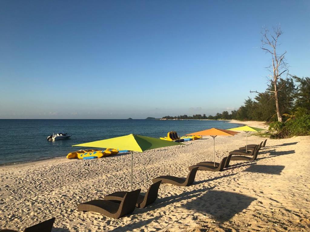 PasarbaruNew Belitung Holiday Resort的海滩上设有椅子和遮阳伞,水面