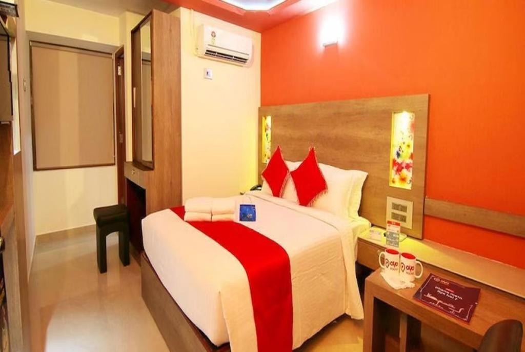 瓦拉纳西GRG Ashiyana Palace Parade Kothi Road Varanasi的一间卧室配有一张带红色墙壁的大床和书桌