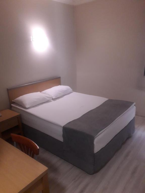 埃尔祖鲁姆OTEL AMİLLER的一间卧室配有一张床、一张桌子和一张桌子