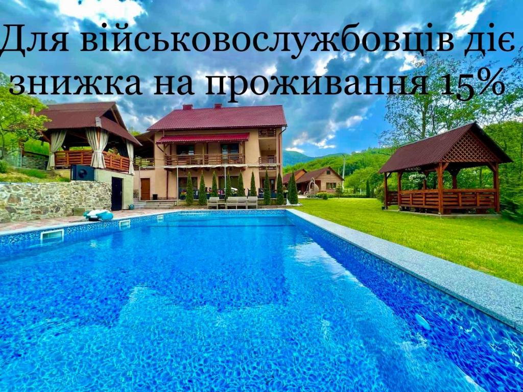 米日吉里亚Купецький Двір的一座大蓝色游泳池,位于房子前