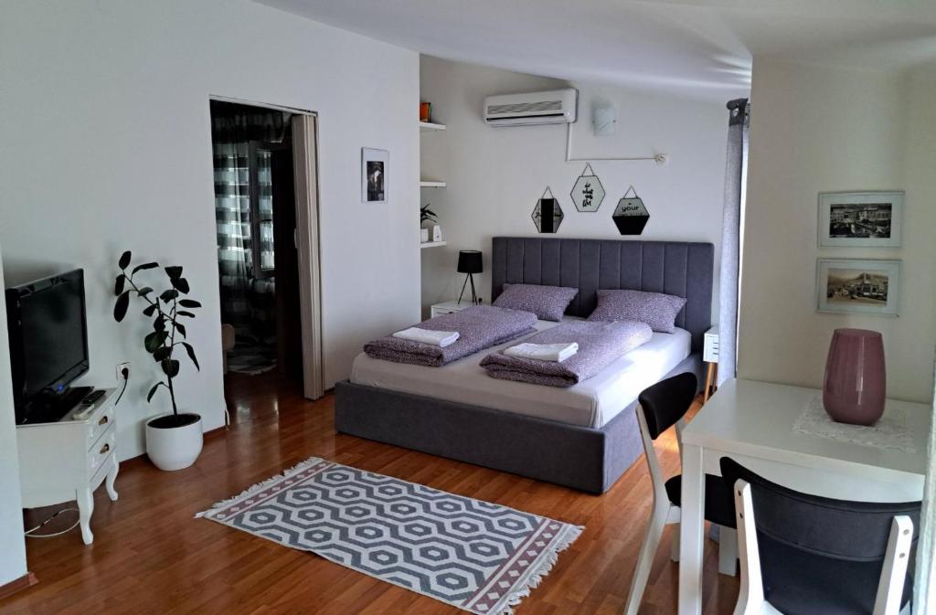 莫斯塔尔西娅公寓酒店的一间卧室配有一张带紫色枕头的床和一张书桌