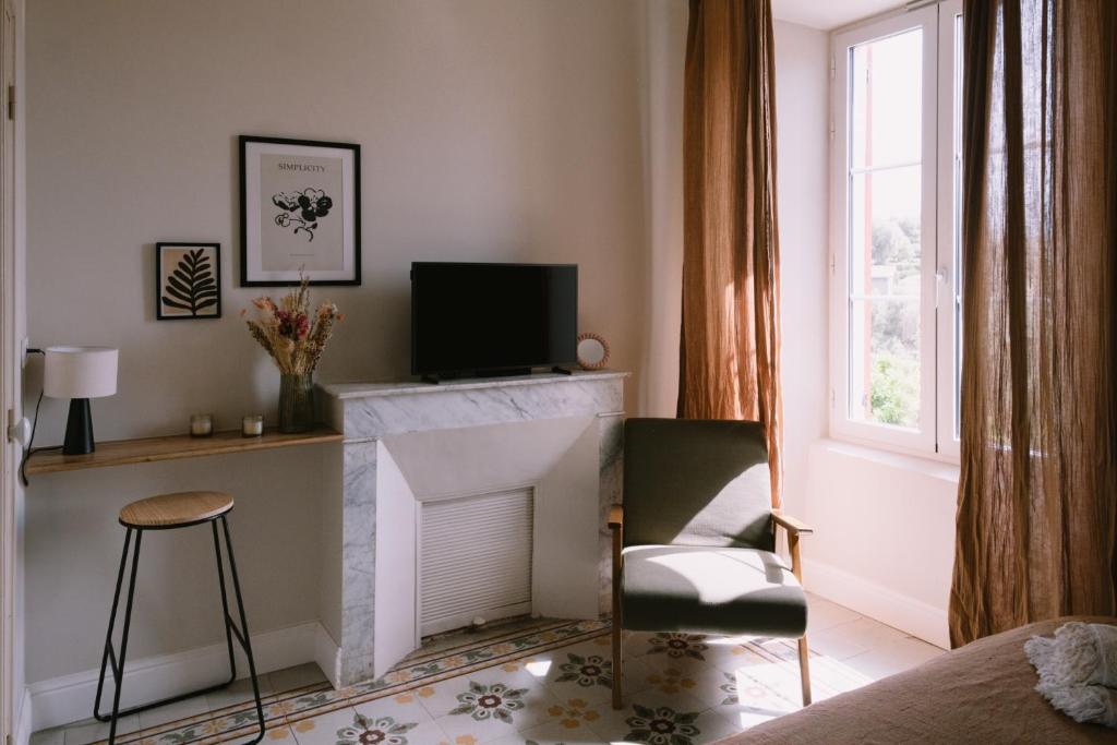 AfaL'Orangeraie d'Afa的客厅设有壁炉、椅子和电视