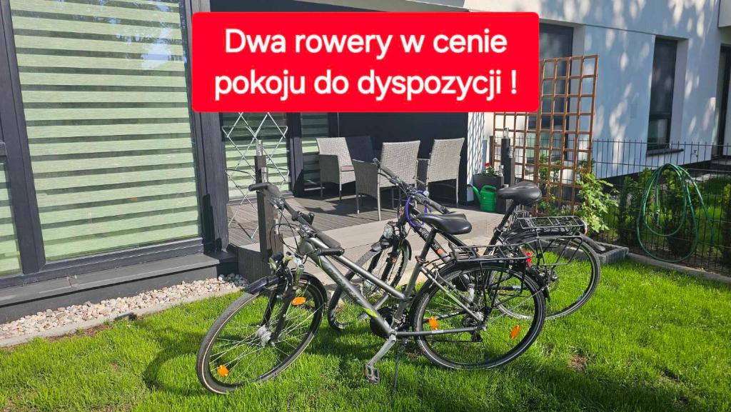 厄尔科Apartament Mono Ełk CENTRUM的两辆自行车停在草地上的一个标志旁边