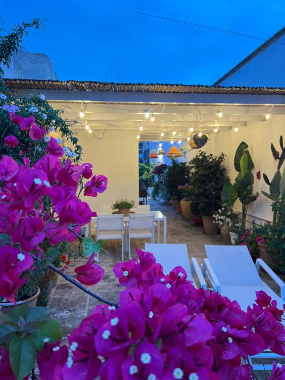 莱切Suite Battisti 7的庭院里种有紫色花卉,配有白色的桌椅