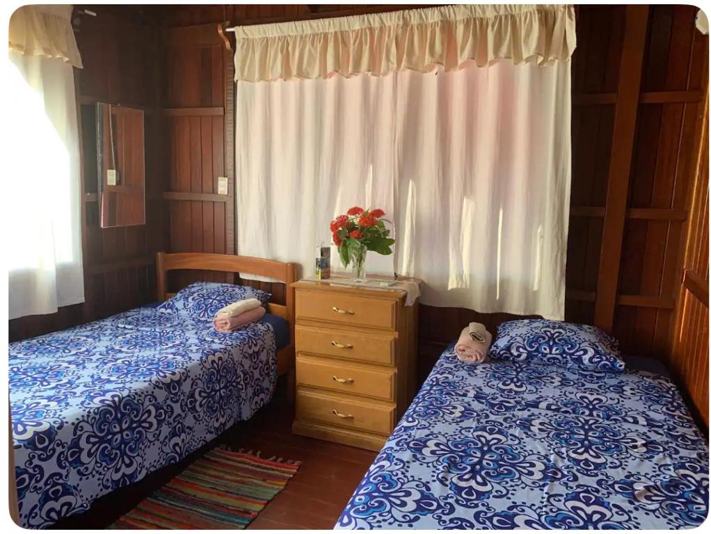 普卡尔帕Casa Bugambilia Pucallpa的一间卧室配有两张床和一个带鲜花的梳妆台。