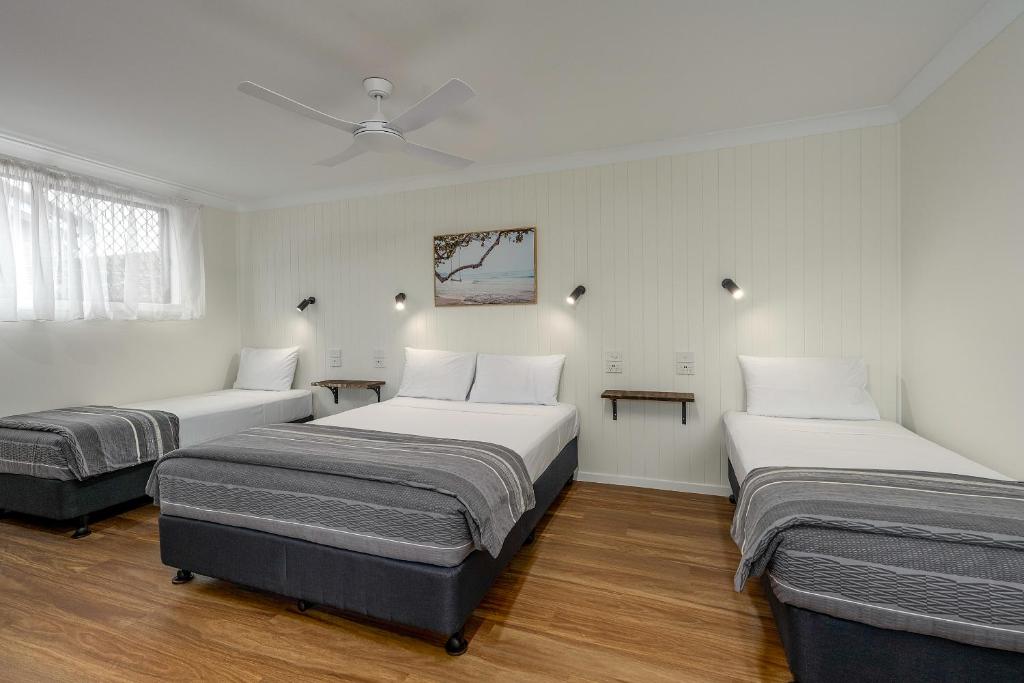 巴利纳海岸汽车旅馆的配有白色墙壁和木地板的客房内的三张床