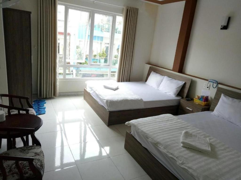 大叻Tường Lan Hotel的酒店客房设有两张床和窗户。