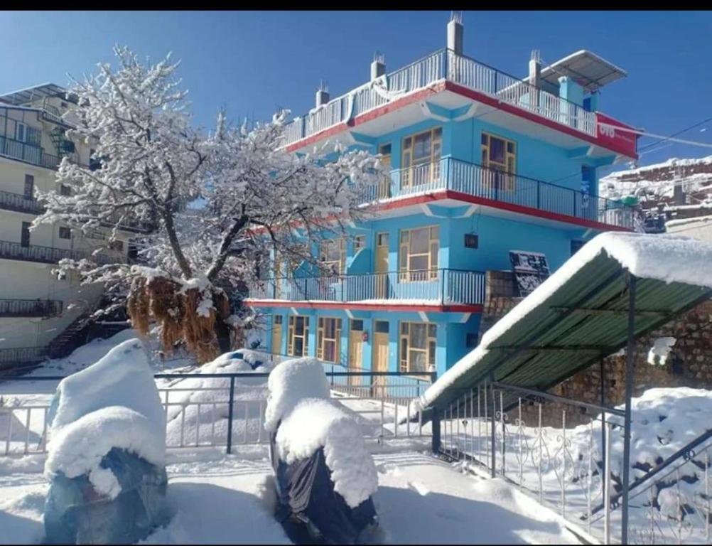 达兰萨拉Mcleodganj Diaries Homestay的一座蓝色的建筑,地面上积雪