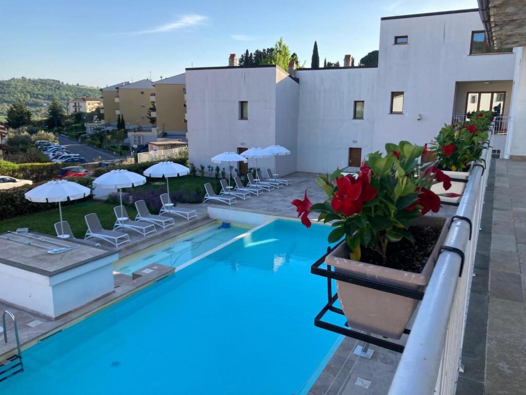 佩拉戈The Florence Hills Resort & Wellness的酒店游泳池设有椅子和遮阳伞